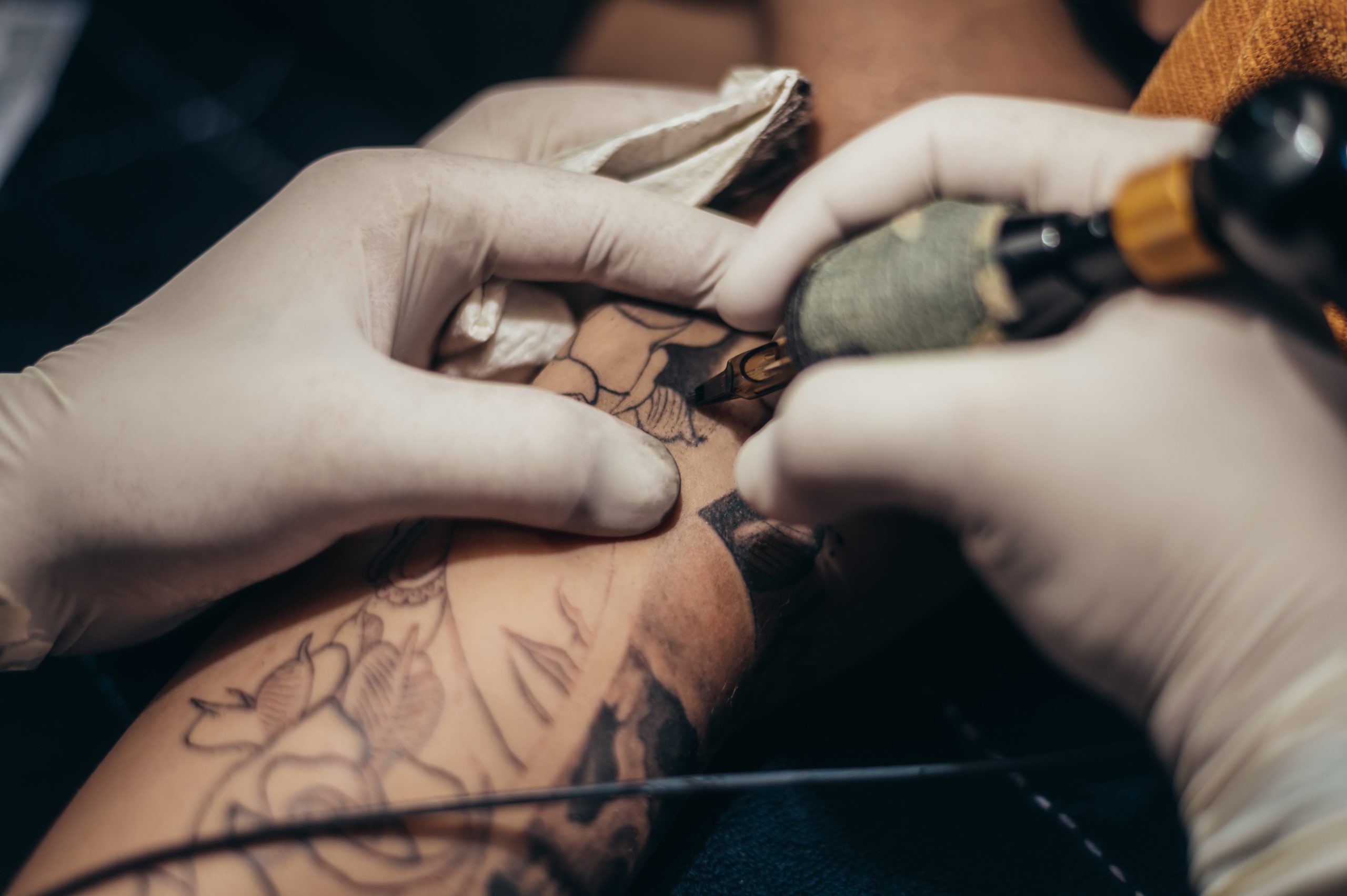 Tattoo artist hands in a white gloves holding a machine while cr